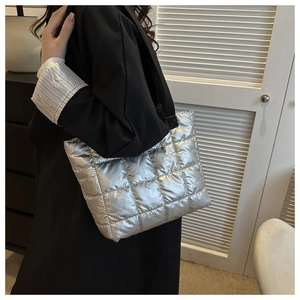 Silver quilted tote bag with metallic finish and black straps shown on a model