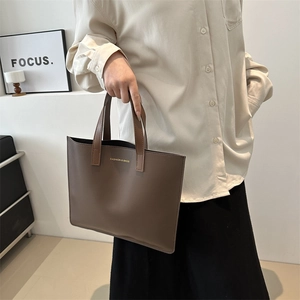 Minimalist dark brown leather tote briefcase with gold lettering for women in a stylish setting