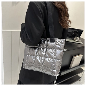 Silver metallic quilted tote bag shown on model in a modern office professional setting