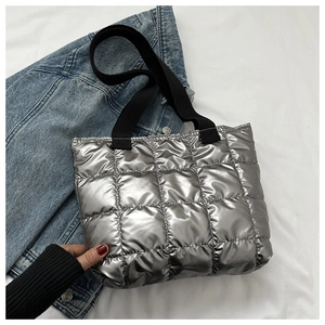 Detailed shot of quilted silver tote bag with shiny metallic texture and black straps