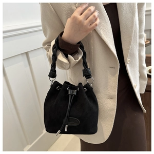 Détail du sac seau noir en daim mat avec poignée tressée et fermeture à cordon