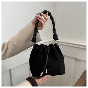 Détail du sac seau en daim noir avec poignée en cuir tressé et fermeture à cordon