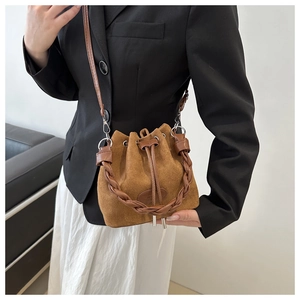 Détail du sac seau en daim marron avec poignée en cuir tressé et fermeture à cordon
