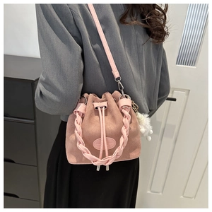 Détail du sac seau rose mat avec poignée tressée et charmant pendentif en peluche blanche