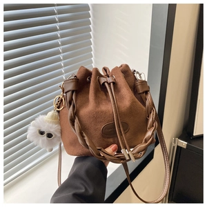 Détail du sac seau en daim marron avec poignée tressée et breloque en peluche douce