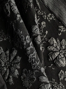 Macro shot of black embossed floral jacquard fabric for elegant evening dresses