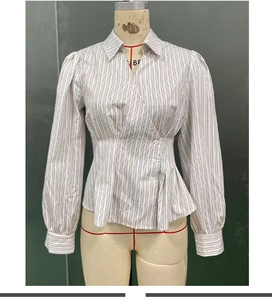 Dettaglio della camicia a righe a maniche lunghe con vita aderente e bottoni