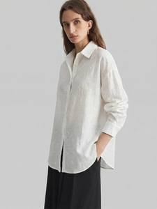 Detail of white crepe shirt showing floral embroidery and fine textured fabric detail