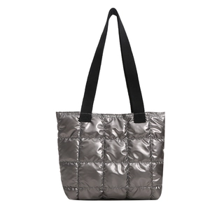 Silver quilted tote bag with metallic finish and black straps for a stylish winter look