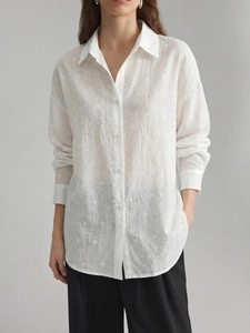 Close-up of white crepe shirt fabric with delicate floral jacquard and button details