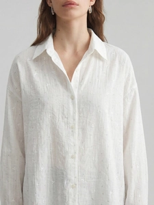 Detailed view of white textured crepe fabric with floral pattern on long sleeve shirt
