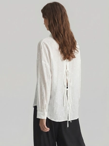 Detail of white long sleeve shirt showing elegant back slit with three delicate tie closures