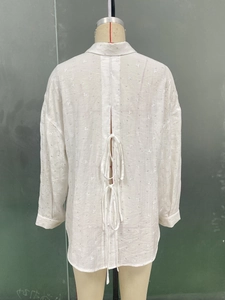 Detail of white long sleeve shirt showing back slit design with self-tie bows and crepe fabric