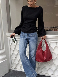 Street style view of a black off-shoulder flare sleeve top with blue wide-leg jeans