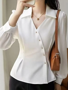 Detail of white satin blouse with asymmetrical gold buttons and lantern sleeves