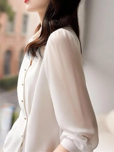 Detailed close-up of white satin shirt featuring elegant golden metal buttons and silk texture