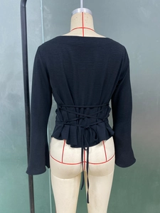 Close-up of black blouse back with criss-cross lace-up ties and ruffle hem detail