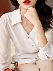 Detail of white satin long sleeve blouse showing V-neck and decorative gold buttons