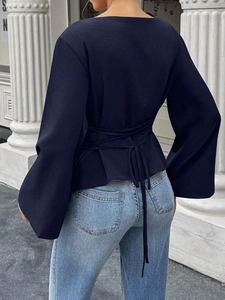 Back view of a deep blue shirt with tie-waist design and elegant flared bell sleeves