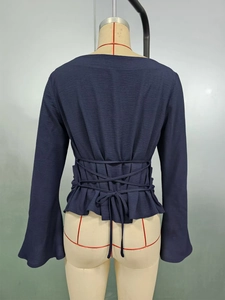 Detail of dark blue blouse showing the lace-up back design and flared trumpet sleeves