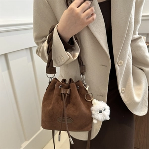 Sac seau en cuir mat marron avec poignée tressée et breloque peluche sur mannequin