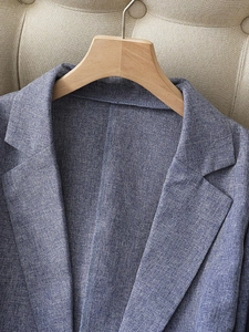 Detailed view of the blue linen-textured fabric on the shoulder and lapel of a blazer