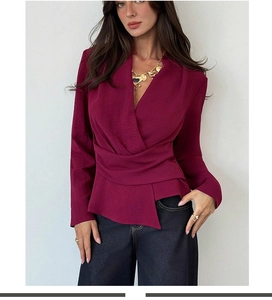 Detail of burgundy wrap-style blouse featuring elegant waist pleats and deep V-neckline