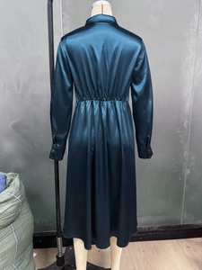Detail of dark green satin dress featuring elastic waist and silk-like glossy fabric