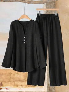 Detail of black V-neck top and wide-leg pants set with textured fabric and wood buttons