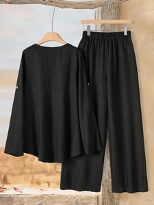 Detail of black long-sleeved top cuff featuring elegant buttons on textured fabric