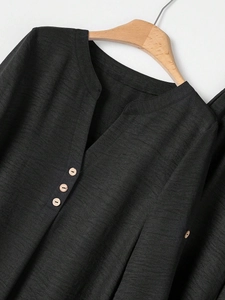 Detail of dark grey textured fabric with V-neckline and wooden buttons on a hanger