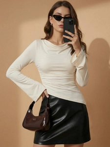 Women's off-white long sleeve ruched top with cowl neck paired with black leather skirt