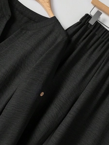 Detailed texture of black linen v-neck top with wooden button and elastic waist pants