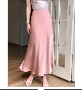 Détail de la jupe longue en satin rose montrant le tissu brillant et le drapé fluide