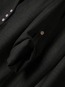 Detail of black textured cotton-linen blouse showing V-neck and wooden buttons