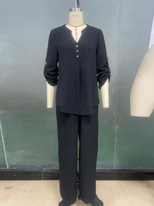 Detail view of black V-neck long sleeve top with wooden buttons and matching trousers set