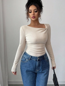 Détail du haut en maille côtelée blanc cassé avec décolleté asymétrique et épaule nouée