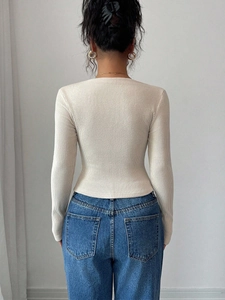 Gros plan sur la texture en maille côtelée ajustée au dos de ce pull de couleur crème