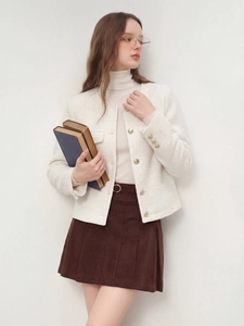 Détail de veste en tweed blanc aux boutons dorés et jupe plissée marron chic
