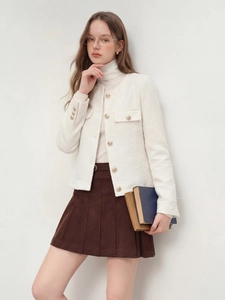 Détail d'une veste en tweed blanc avec boutons dorés et jupe plissée marron