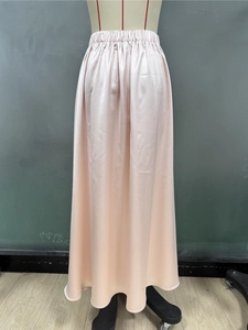 Detail of light pink satin maxi skirt showing glossy fabric texture and elastic waist