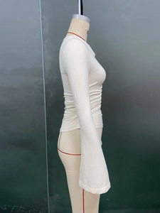 Detail of white long sleeve top featuring elastic knit fabric and flared cuffs on mannequin