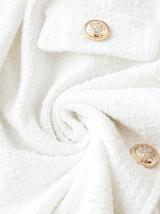 Detail of white tweed fabric with embossed vintage gold metal buttons on a jacket