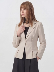 Détail d'un blazer cintré beige clair avec plis à la taille et fermeture à un bouton