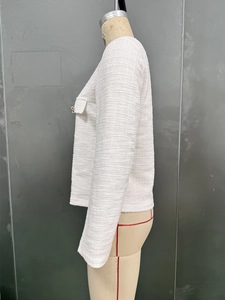 Detail view of ivory tweed jacket fabric texture and decorative pocket flap design