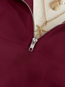 Close-up of metal zipper detail on burgundy oversized sweatshirt with ribbed texture