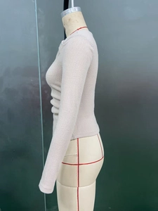 Détail d'un pull en maille côtelée blanc cassé avec une texture à rayures verticales