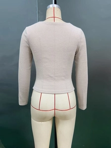 Détail du pull en maille abricot avec texture côtelée verticale et col rond élégant
