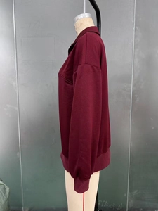 Detail of burgundy half-zip sweatshirt featuring ribbed cuffs and loose fit style