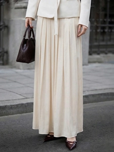 Detailed close-up of an elegant cream pleated maxi skirt showing fabric texture and drape